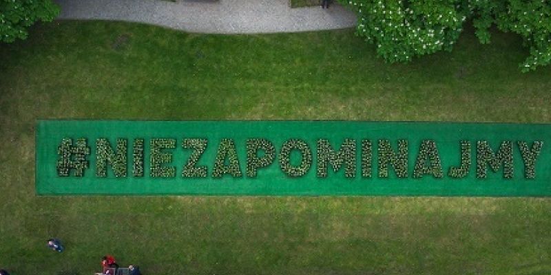 #NieZapominajmy – kwietny napis pod pomnikiem Nike pamięci ofiar COVID